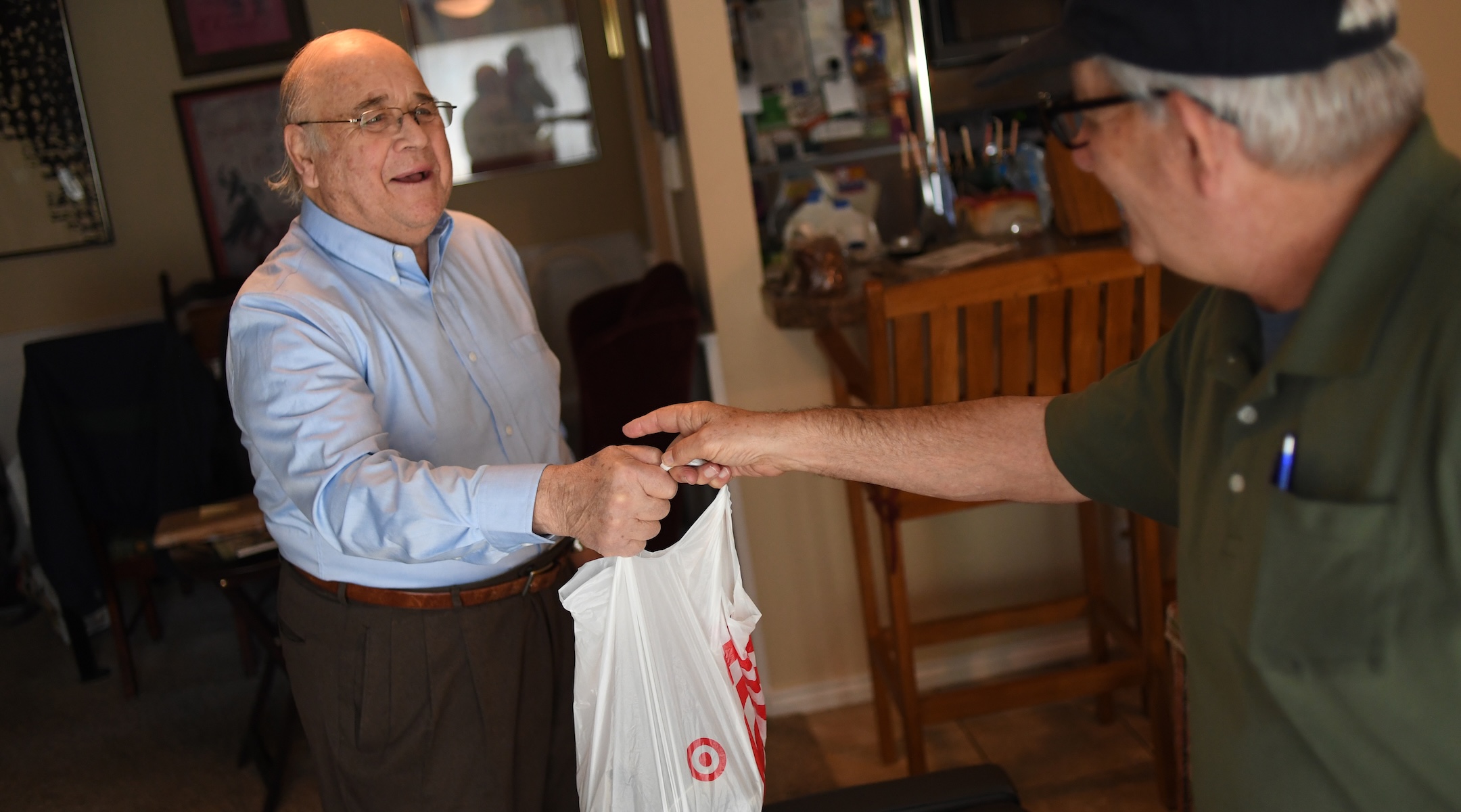 Holocaust survivor Rudi Jocobsen, left, takes a bag of food from Uriel Rauff, who works for Jewish Family Service Colorado as a driver for the kosher Meals on Wheels Program in Denver, Colorado, on December 19, 2017. (RJ Sangosti/The Denver Post via Getty Images)