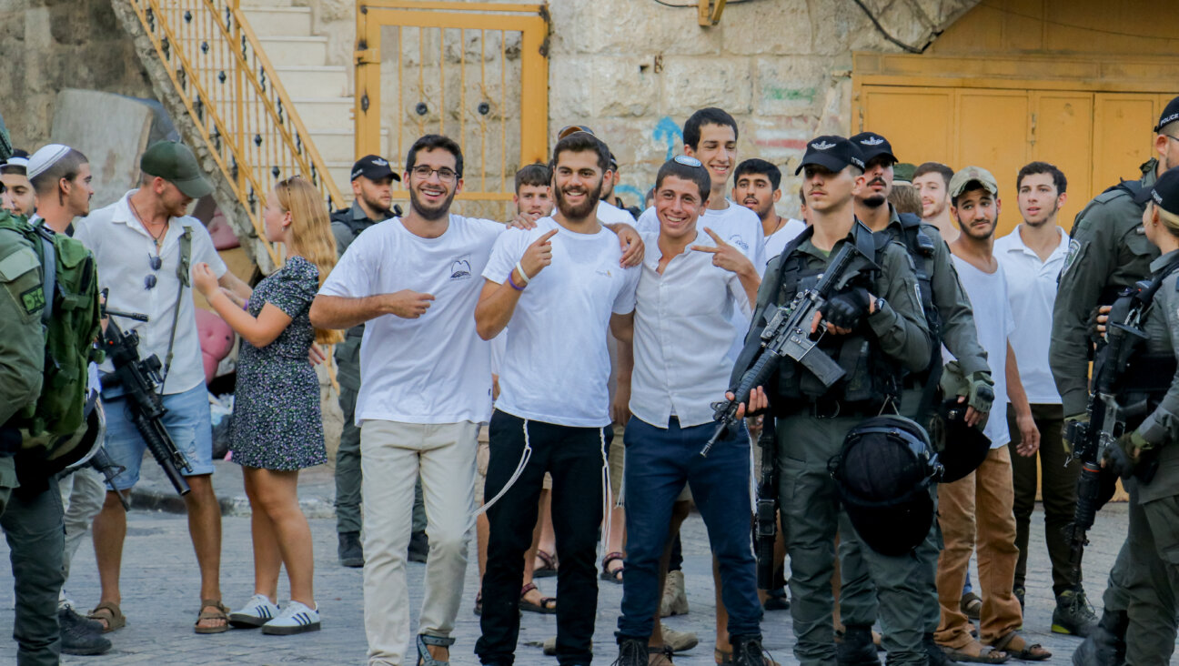 Settlers in the West Bank pose for a photo as Israeli soldiers stand nearby during a march in Hebron, Sept. 28, 2024. 