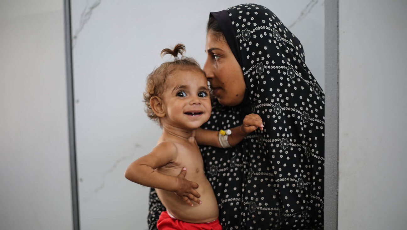 A Palestinian woman holds a malnourished child at Al-Awda hospital in the Nuseirat refugee camp in the central Gaza Strip on June 30.