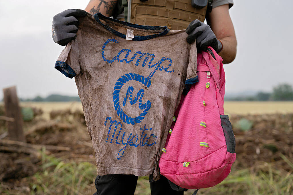 A search and rescue volunteer holds a T-shirt and backpack with the words Camp Mystic on them in Comfort, Texas on July 6. The volunteer found the belongings along the Guadalupe River near Ingram, Texas.  